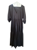Modify Thrift Zara jet black tiered midi dress with V-neck and three-quarter puff sleeves hanging in a boutique.
