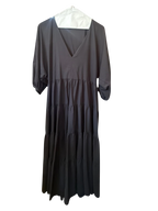 Modify Thrift Zara jet black tiered midi dress with V-neck and three-quarter puff sleeves hanging in a boutique.